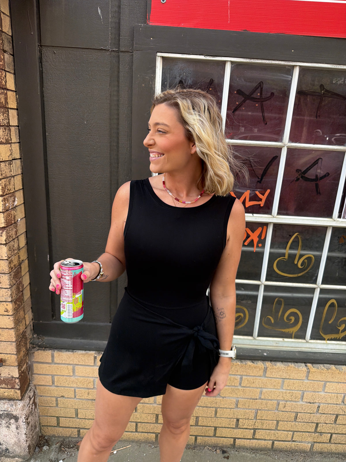 Woman wearing a black wrap athletic dress with a scoop neck & scoop back