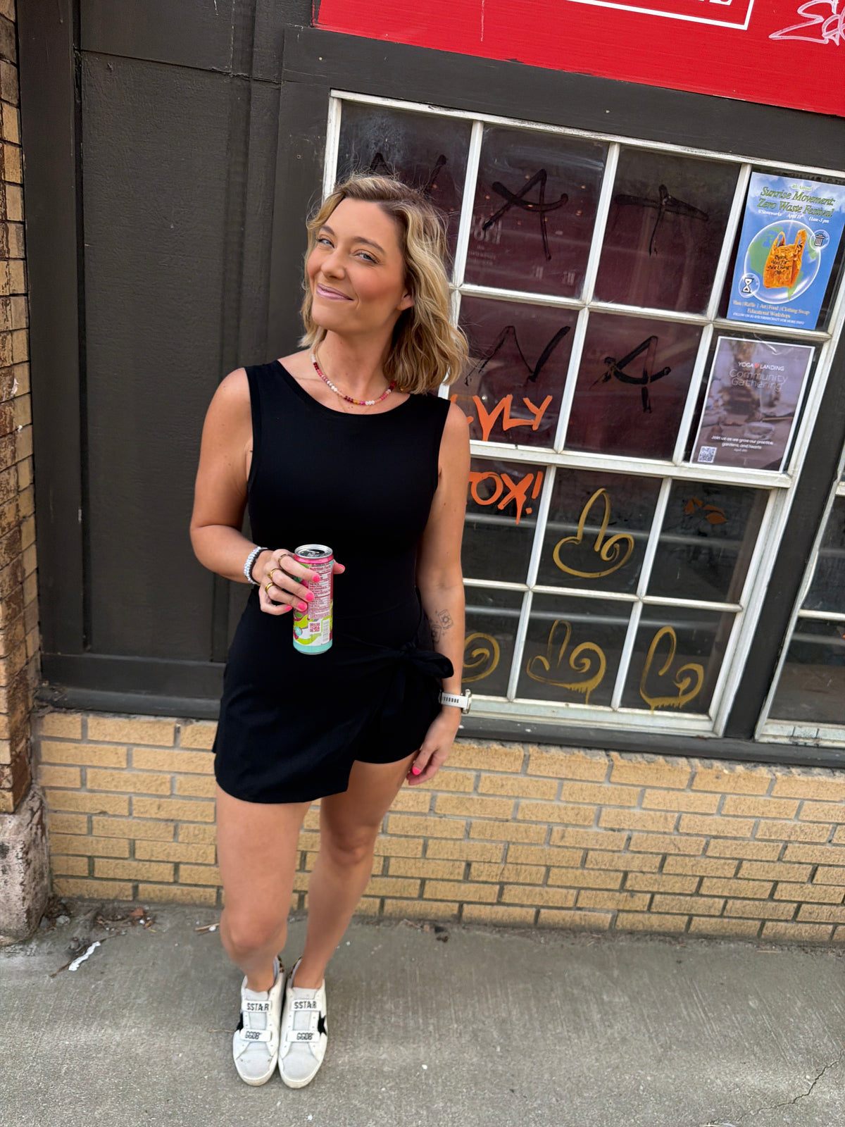 Woman wearing a black wrap athletic dress with a scoop neck & scoop back