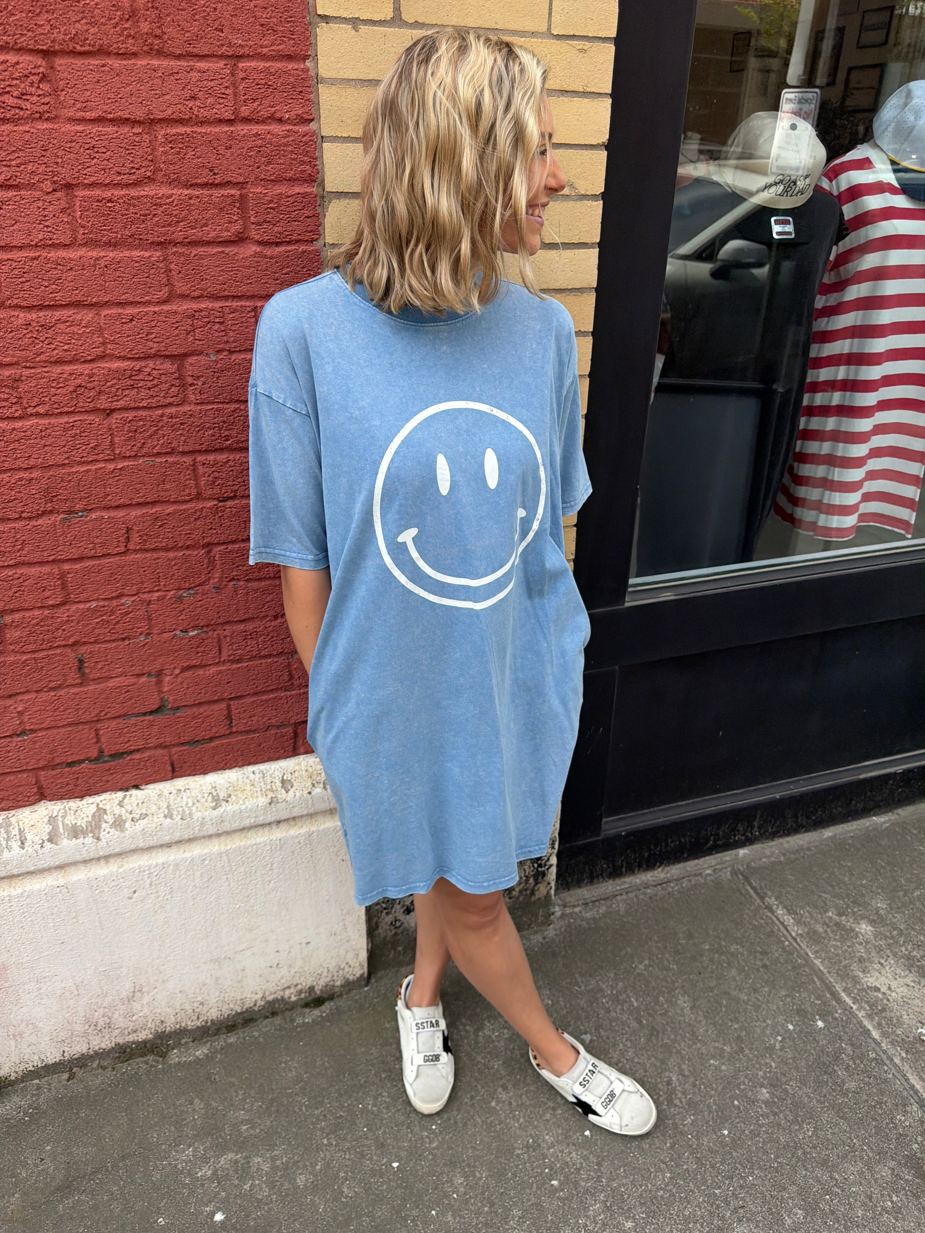 woman wearing a baby blue t-shirt dress with a white smiley face on it.